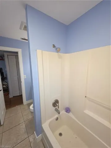 Full bathroom with shower / washtub combination and light tile patterned flooring
