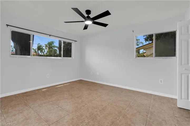 Spacious room featuring neutral wall tones, large-format tile flooring, and a modern ceiling fan with integrated lighting
