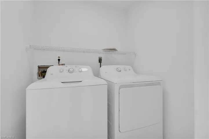Dedicated laundry area featuring white walls and a wire shelving unit