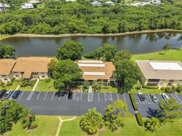 Aerial perspective of a multi-unit residential property featuring a large body of water and lush green landscaping