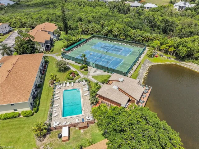 Aerial perspective highlighting community amenities including a swimming pool with lounge area, multiple tennis courts, and a waterfront building with an outdoor patio overlooking the lake