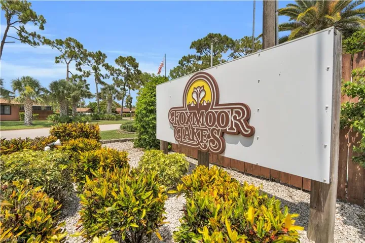 Community entrance signage featuring brown dimensional lettering, a white background, and a decorative emblem