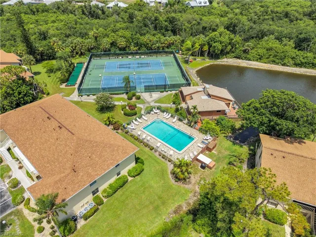 Community amenities featuring a swimming pool with surrounding lounge chairs, tennis courts, and a waterfront building with an expansive deck