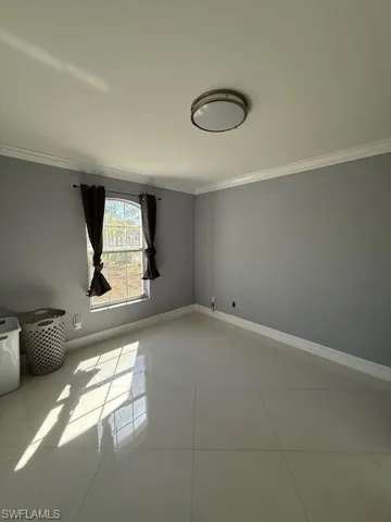Unfurnished room with crown molding and light tile patterned flooring