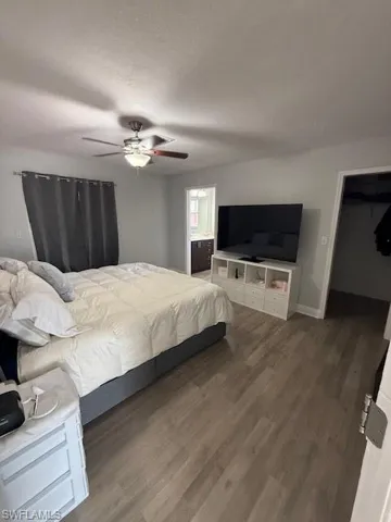 Bedroom with wood finished floors, ceiling fan, a textured ceiling, and a walk in closet