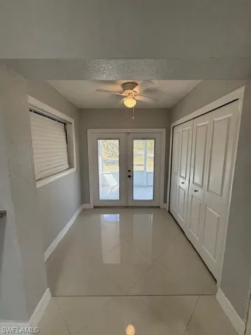 Doorway to outside with french doors, a ceiling fan, and a textured wall