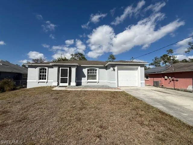 Ranch-style home featuring driveway, stucco siding, a garage, and a front lawn