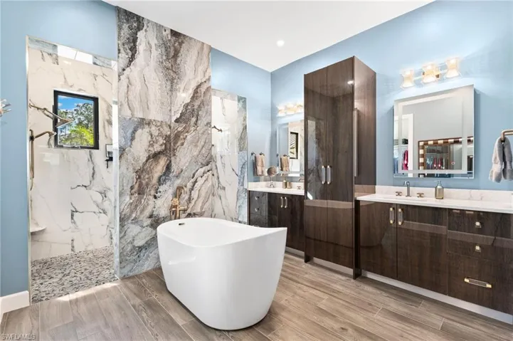Primary bath offers a modern free-standing tub, oversized walk-in shower with multiple shower heads, dual vanities with custom cabinetry