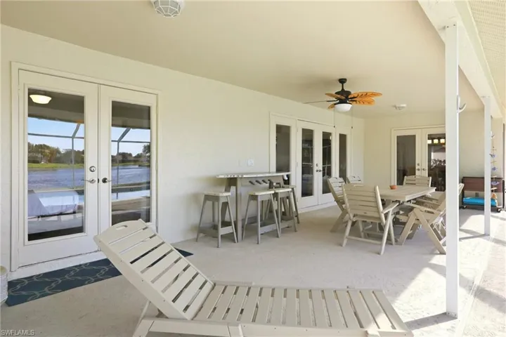 View of patio / terrace featuring french doors, outdoor dining space, ceiling fan, and a water view