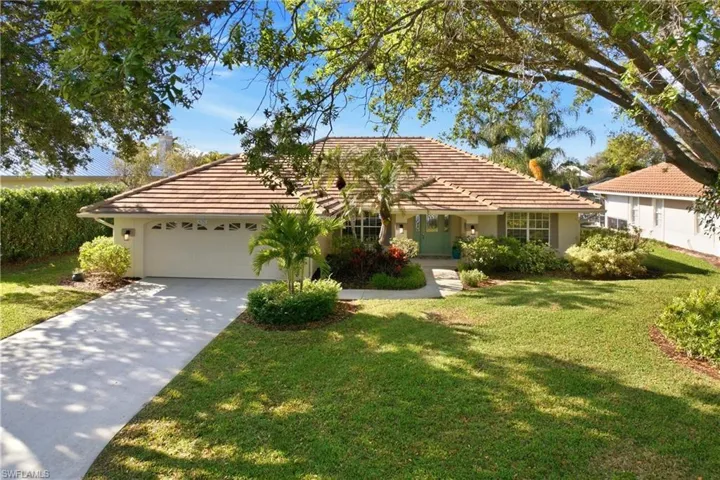 Ranch-style home featuring a garage, a tiled roof, and a front yard
