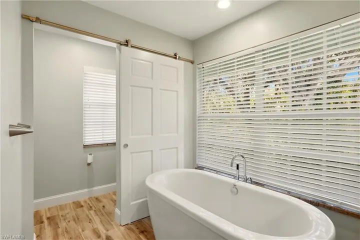 Bathroom with light wood-style floors and a freestanding bath
