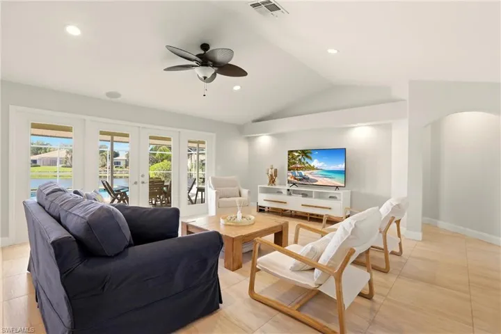 Living room featuring ceiling fan, french doors, lofted ceiling, recessed lighting, and arched walkways