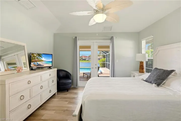 Bedroom featuring french doors, access to outside, light wood finished floors, ceiling fan, and vaulted ceiling