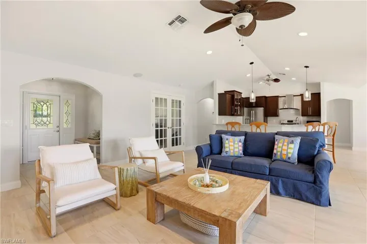 Living room with arched walkways, ceiling fan, and lofted ceiling