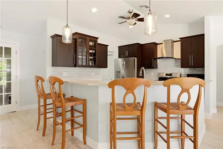 Kitchen with dark wood finish cabinetry, a breakfast bar, decorative backsplash, and vaulted ceiling