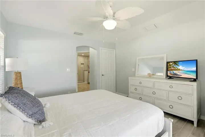 Bedroom with ceiling fan, arched walkways, and light wood-type flooring