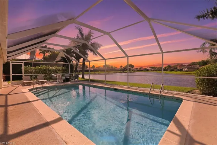 Outdoor pool with glass enclosure, a sunroom, a water view, a patio, and a residential view