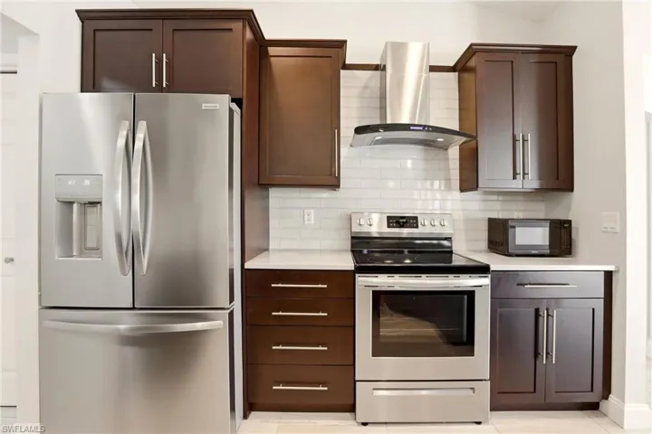 Kitchen featuring stainless steel appliances, dark wood finish cabinets, and light tile patterned flooring
