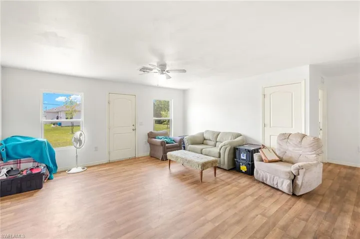 Living area featuring a ceiling fan, wood finished floors, and baseboards