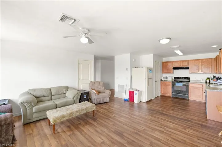 Living room with dark wood-type flooring, ceiling fan, and baseboards