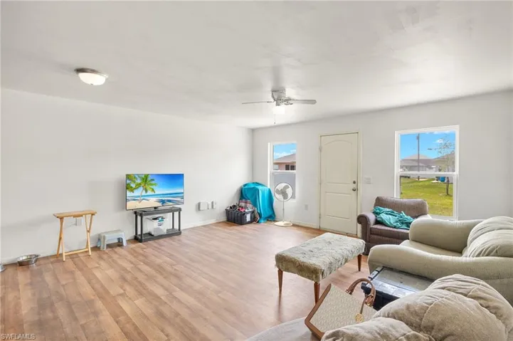 Living area with wood finished floors, healthy amount of natural light, and ceiling fan