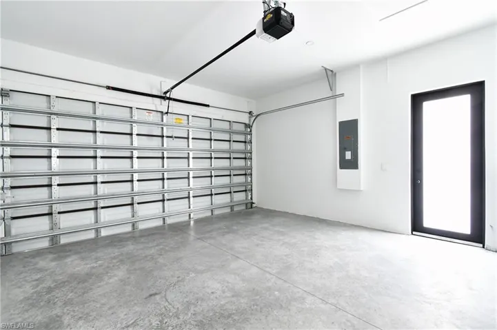 Spacious garage featuring a concrete floor, white walls, and an automatic garage door opener
