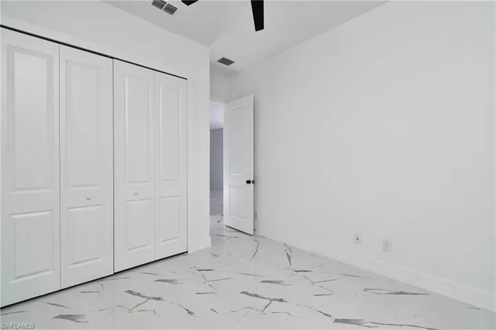 White panel bi-fold closet doors complement the light-toned walls and large format tile flooring