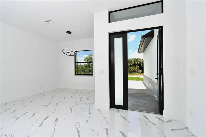 Modern entry area featuring a wide front door with frosted glass panel and transom window