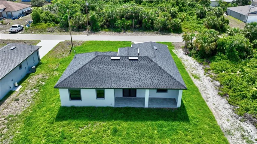 Newly constructed residence featuring a dark shingle roof, white stucco exterior, and a covered patio