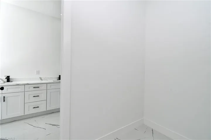 Double vanity with white shaker-style cabinetry, quartz countertop, and black fixtures