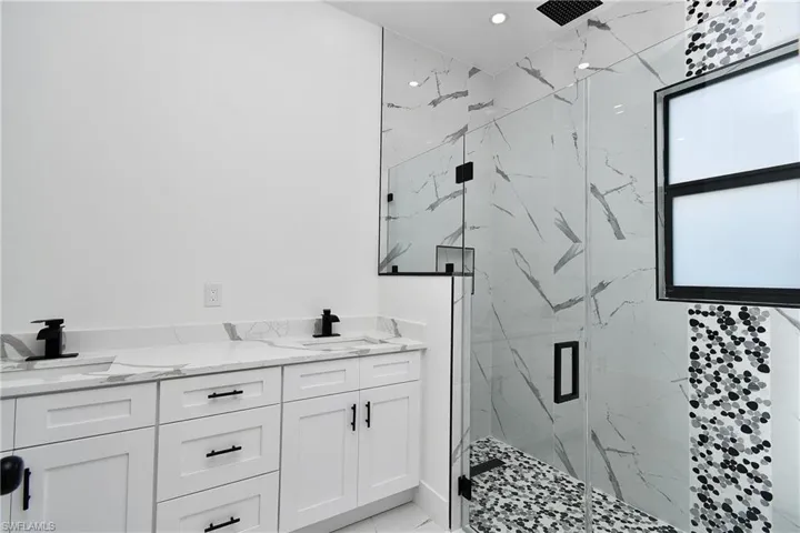 Bathroom featuring a double vanity with white cabinetry and stone countertops