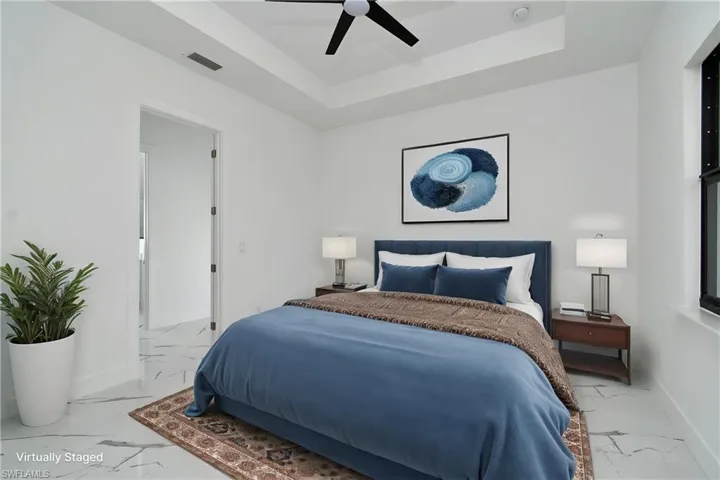 Bedroom featuring a tray ceiling, ceiling fan, and white tile flooring