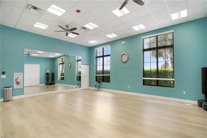 Exercise area with a ceiling fan and a paneled ceiling