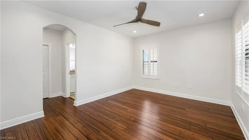Unfurnished room featuring ceiling fan, dark wood-type flooring, arched walkways, and recessed lighting