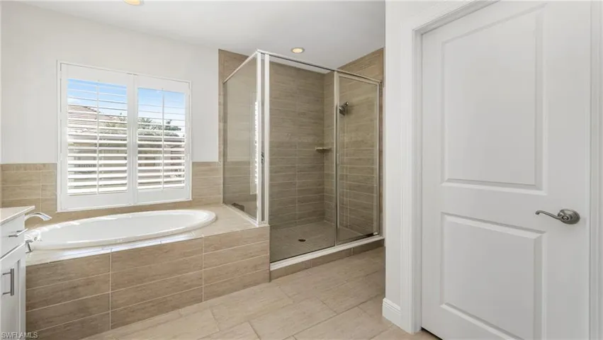 Bathroom with a shower stall, a garden tub, vanity, and recessed lighting