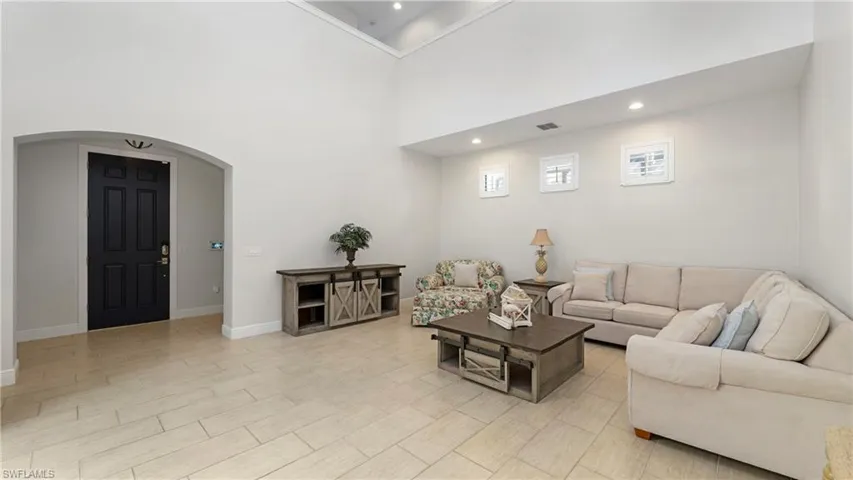 Living area with arched walkways, a high ceiling, and recessed lighting