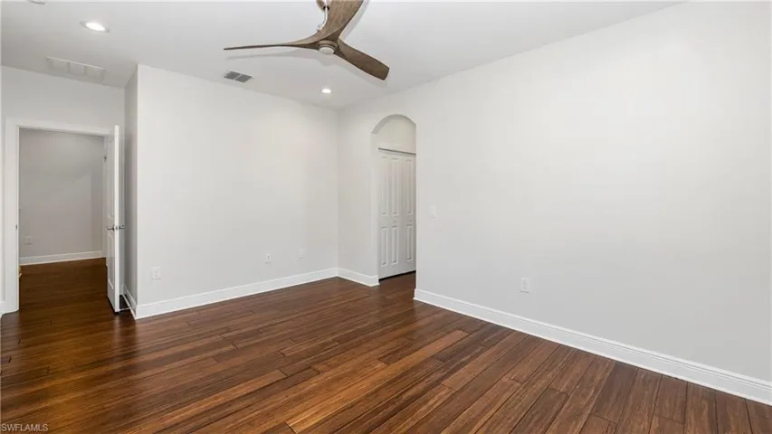 Spare room with arched walkways, ceiling fan, recessed lighting, and dark wood-type flooring