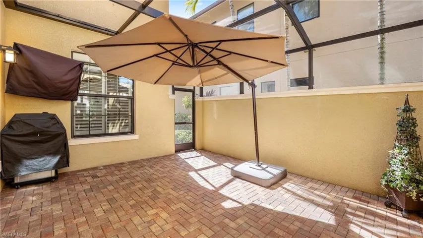 View of patio featuring area for grilling and glass enclosure