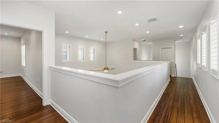 Hall with dark wood-style flooring, healthy amount of natural light, and recessed lighting