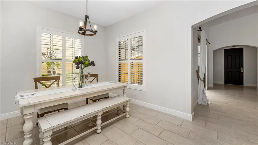 Dining room with arched walkways, a chandelier, and wood tiled floors