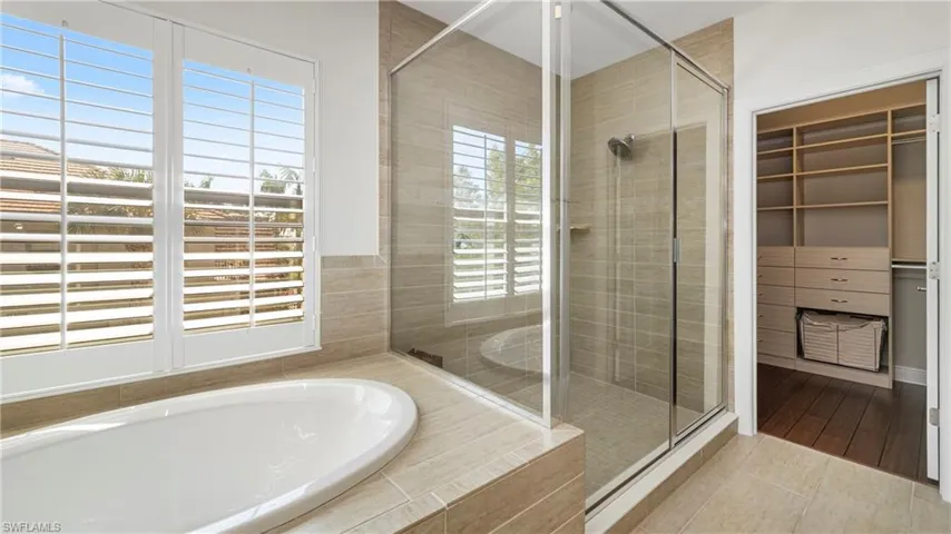 Full bath with a shower stall, a garden tub, a walk in closet, and tile patterned flooring