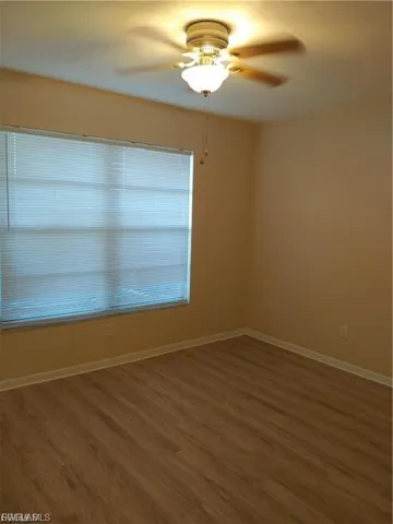 Wood-finish flooring, ceiling fan with integrated lighting, and window blinds