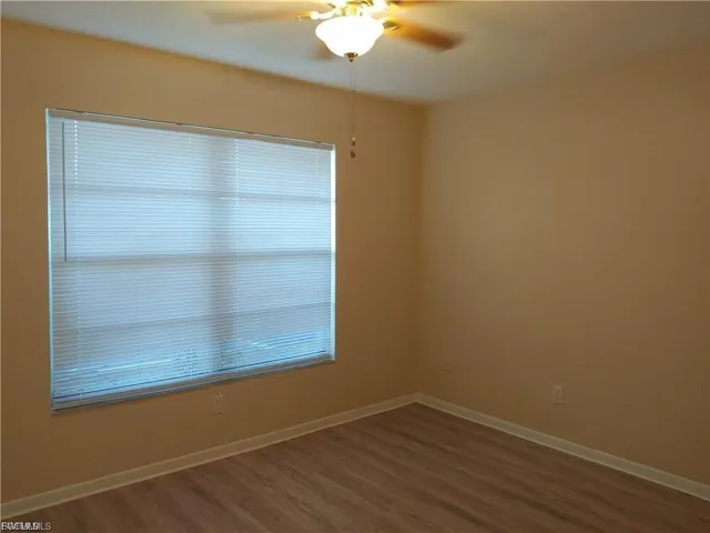 Room featuring wood-finish flooring, a window with horizontal blinds, and a ceiling fan with integrated lighting