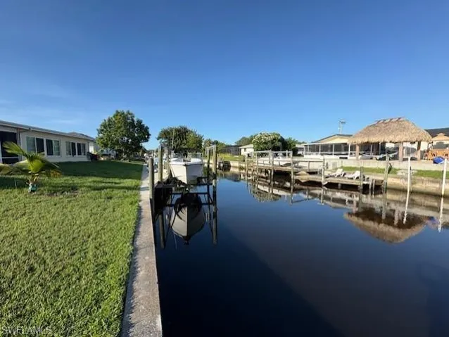 Dock area with boat lift, a lawn, and a water view