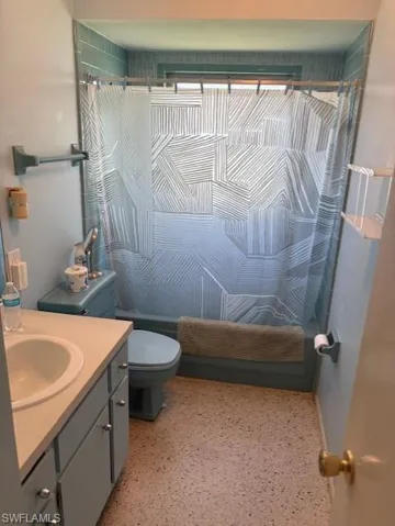 Full bath with vanity and speckled floor