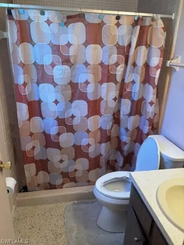 Full bathroom with speckle patterned floor, vanity, and tiled shower