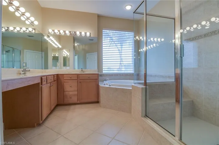 Full bathroom with double vanity, a shower stall, a bath, and light tile patterned flooring