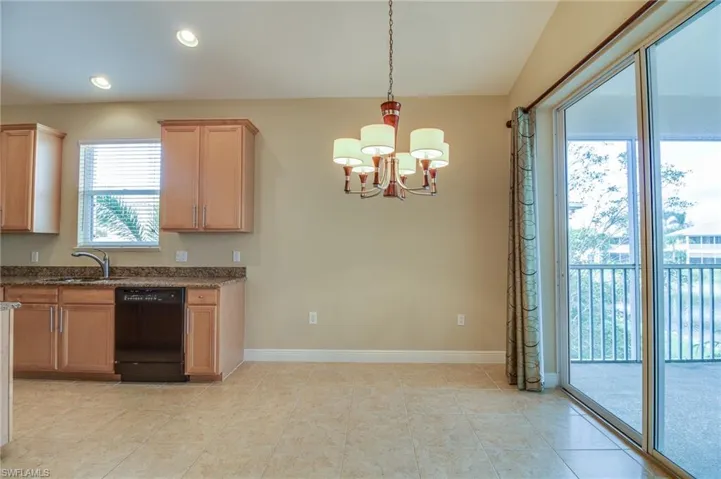 Kitchen with dark stone counters, black dishwasher, a chandelier, decorative light fixtures, and recessed lighting