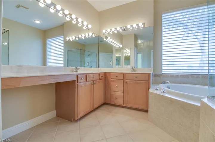 Full bath with a stall shower, double vanity, a bath, and light tile patterned floors