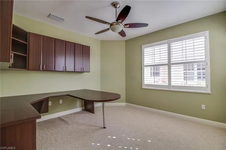 Unfurnished office with light colored carpet, a ceiling fan, and built in study area